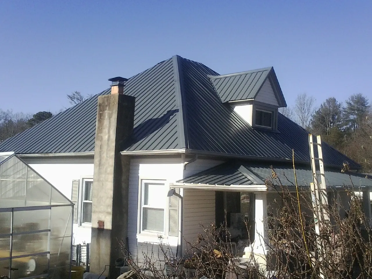 Dark blue standing seam metal roof on a white farmhouse with dormer — Slate & Tile Roof Repair by Roofing Brothers in Capitola