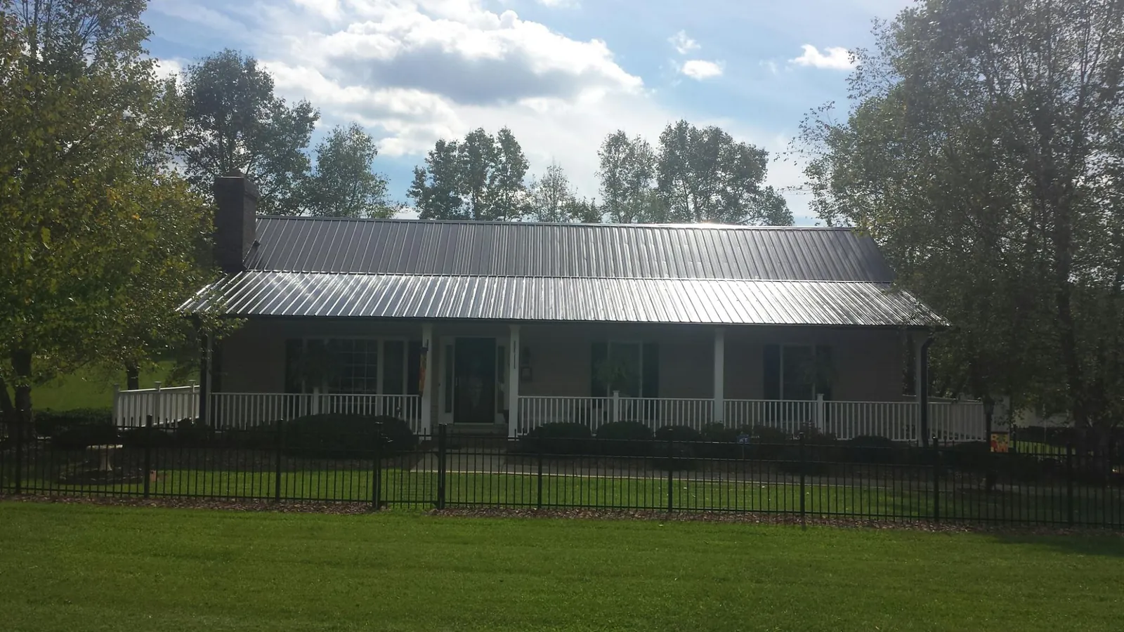 Gray metal roof on a brick ranch with a full width front porch — Gutter Guard Installation work by our crew in Capitola