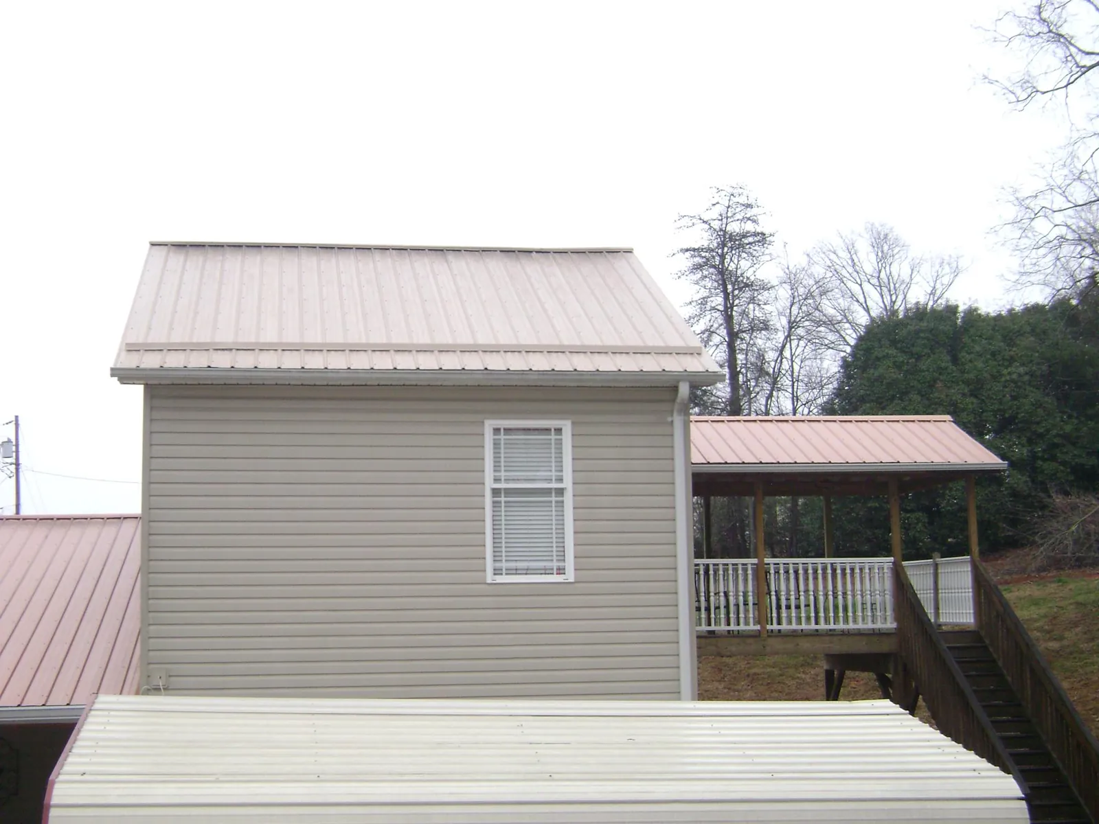 Tan metal roofs on a two story addition and attached porch, from a Roof Replacement job in Capitola